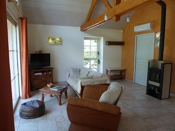 A living room with a sofa, a television on a wooden cabinet, a fireplace, and a window with curtains.