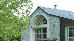 A stone building with a fenced yard, a wooden deck, and a white bird in the background. - Au Bas Chalonge Gite in Ligné (Ligné)