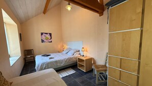 A bedroom with a bed, bedside tables, a chair, a wooden wardrobe, a painting, and a window. - Au Bas Chalonge Gite in Ligné (Ligné)