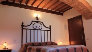 Une chambre avec un plafond en bois, un lit doté d’une tête de lit, deux lampes de chevet et une porte.