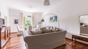Una sala de estar moderna con un sofá, una mesa de comedor, sillas, un televisor y obras de arte en las paredes.