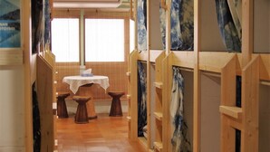 A hallway with wooden partitions, a table with a white tablecloth, and stools. - Kichinan - Hostel (Osaka)