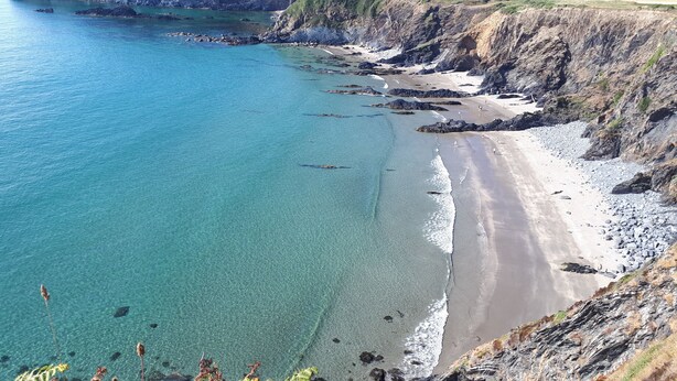 A coastal landscape with clear turquoise waters, a sandy beach, and rocky cliffs. - Escape To This Hidden Gem & Relax In Tranquility - Beaches & Coastal Path Nearby (st nicholas)