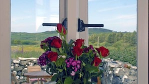A window with a view of a rural landscape, a wooden table, and a flower arrangement. - Escape To This Hidden Gem & Relax In Tranquility - Beaches & Coastal Path Nearby (st nicholas)