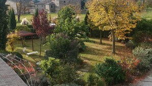 Ein Garten mit einer Pergola, einer Sitzgelegenheit und Blick auf ein Gebäude im Hintergrund.