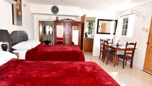 A hotel room with two beds, a dining table with chairs, a mirror, and a clock on the wall. - Cozy Cottage, 5 minutes walk to beach, beautiful garden perfect relaxation spot (Ocho Rios)