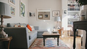 A living room with a grey sofa, a wooden coffee table, and a patterned rug.