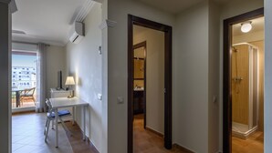 Habitación de hotel con comedor, baño con ducha y vistas a la ciudad.