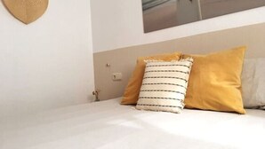 A bedroom with a bed, a heart-shaped wall hanging, and a framed picture on the wall.