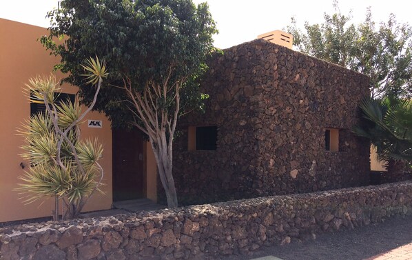A building with a stone facade and a door, surrounded by trees and a stone wall. - Beautiful house ideal for families with small children pool. (La Oliva)