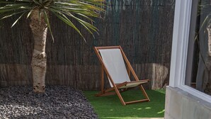A swimming pool with a tiled edge, a wooden chair, and a palm tree.
