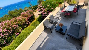 Une terrasse avec des sièges extérieurs, une vue sur la mer et une montagne en arrière-plan.