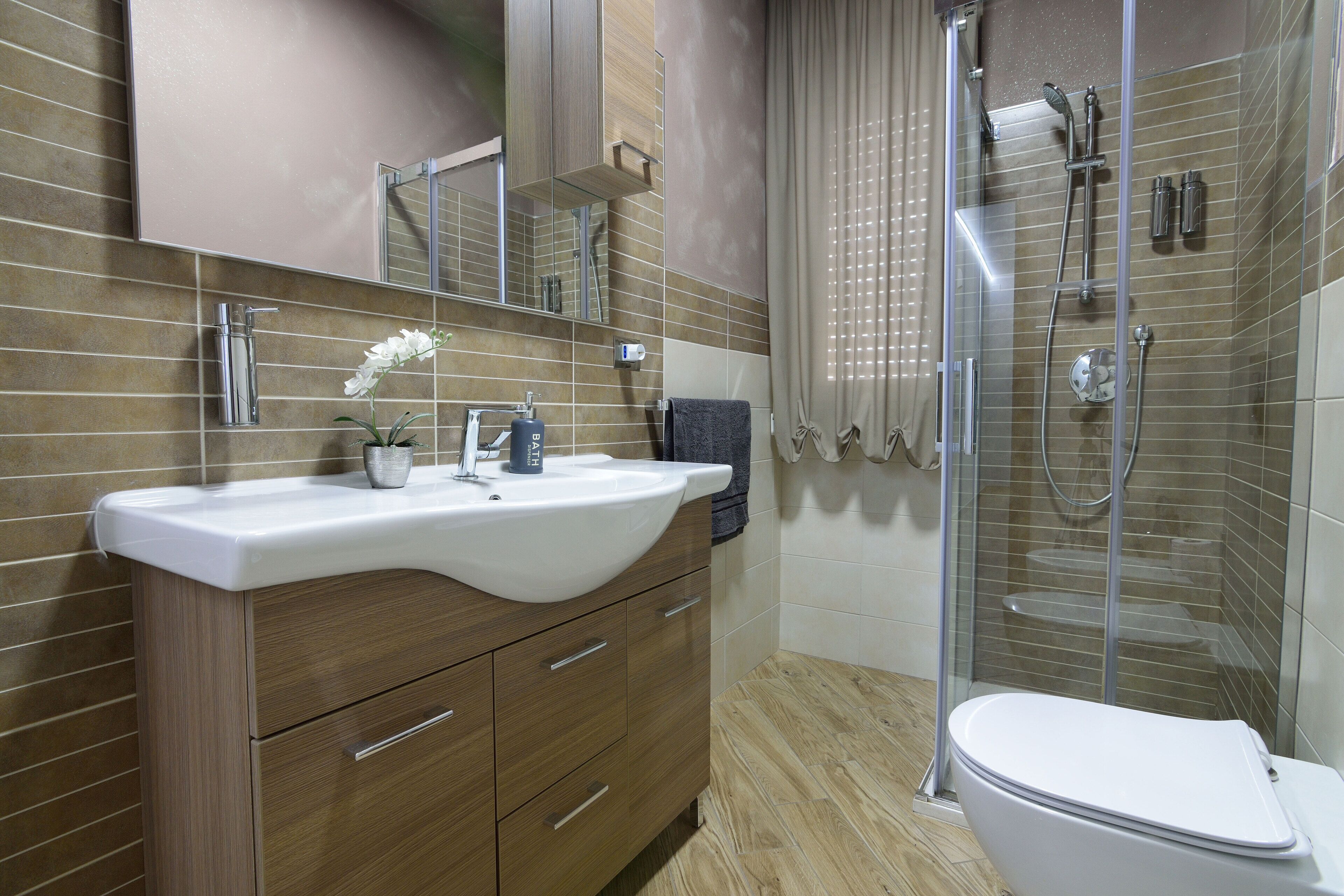 Een moderne badkamer met een groot wastafel, spiegel en douche.