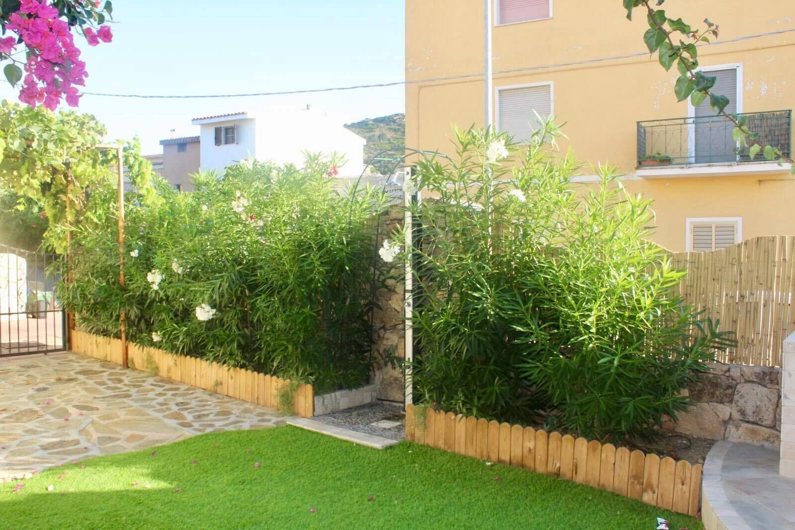 Un quartier résidentiel avec un sentier en pierre menant à une clôture en bois, une pelouse bien entretenue et un bâtiment doté d’un balcon.