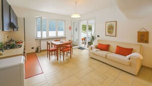 A modern kitchen with a dining area, a white sofa, and a large window. - Villa L'Approdo, Porlezza, Italy (Porlezza)