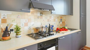 A modern kitchen with grey cabinets, a tiled backsplash, a gas stove, and a variety of kitchen utensils and appliances. - Villa L'Approdo, Porlezza, Italy (Porlezza)
