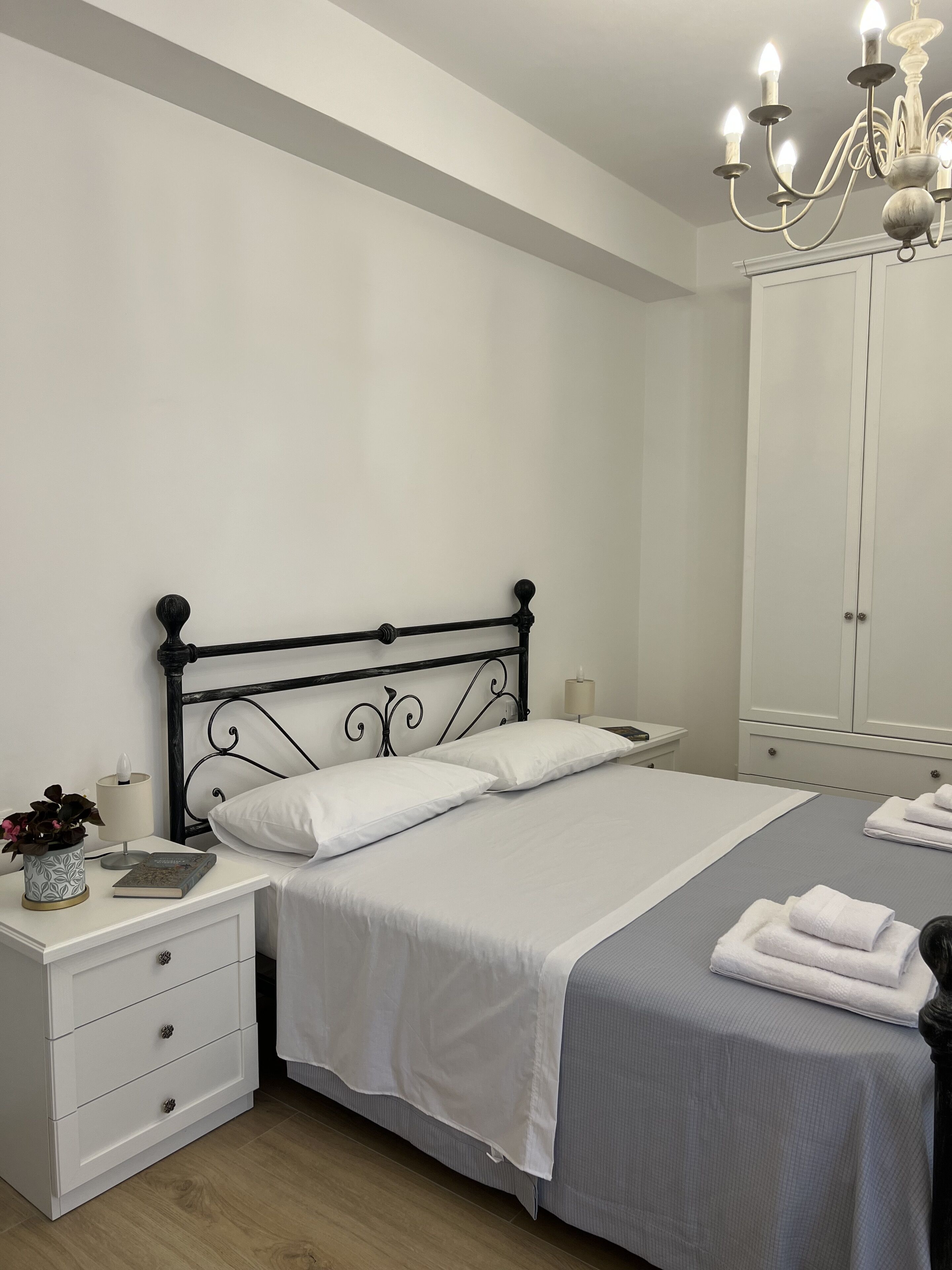 Un dormitorio ordenado con cama, mesita de noche, lámpara y armario.