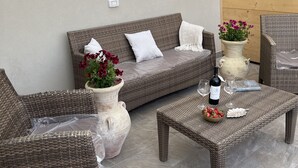An outdoor seating area with wicker furniture, a table with wine and fruit, and a potted plant. - Bright, air-conditioned apartment with a large terrace a few steps from the sea (Terrasini)