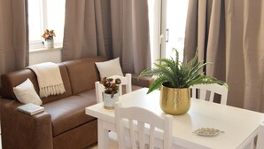 A cozy living area with a brown sofa, white chairs, a small table, and a chandelier. - Bright, air-conditioned apartment with a large terrace a few steps from the sea (Terrasini)