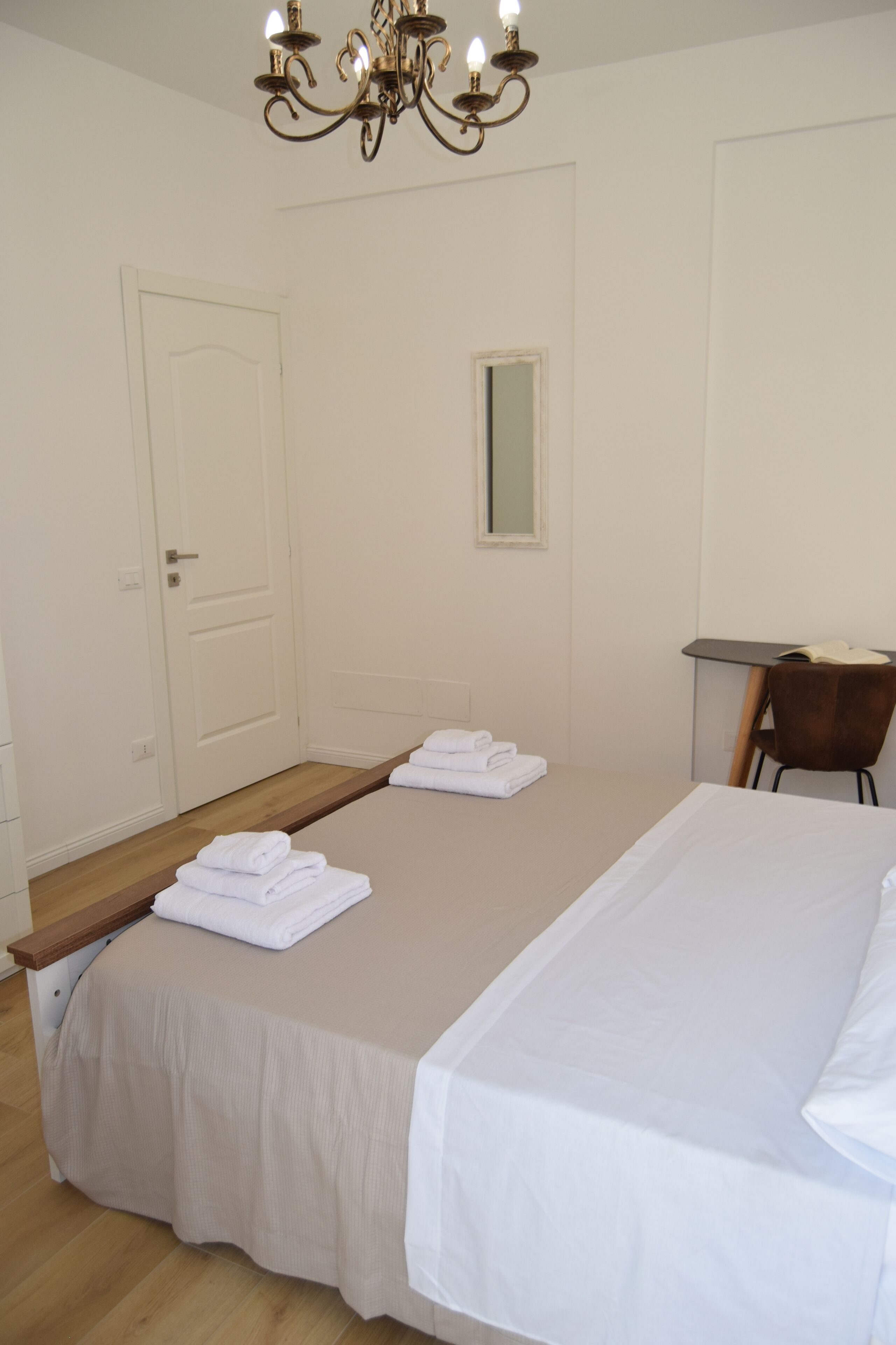 Habitació d'hotel amb un llit gran, un escriptori, una cadira i un penjallum.