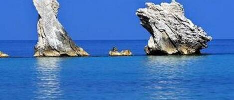 A coastal scene with large rock formations emerging from the water.