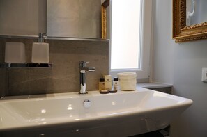 Un baño con un lavamanos grande blanco, un espejo y artículos de aseo sobre la encimera.