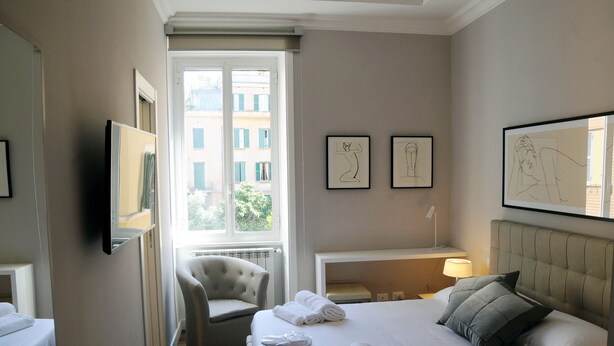 Una camera d'albergo con un letto, una sedia, una scrivania e opere d'arte alle pareti.