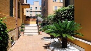 Un cortile stretto con pavimento piastrellato, una palma e piante in vaso.