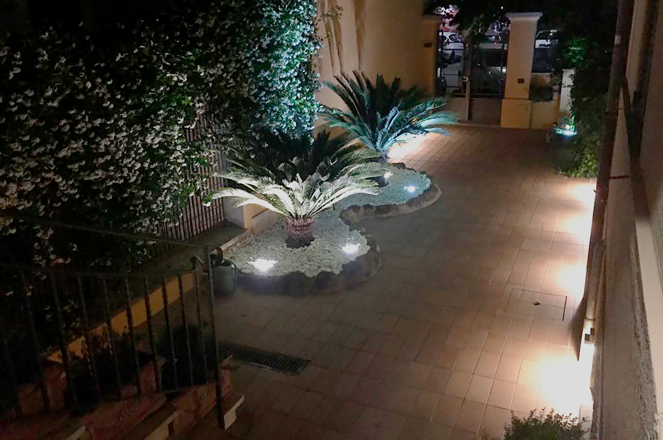 Une cour intérieure agrémentée d’une fontaine centrale, entourée de plantes et dotée d’un sol carrelé.