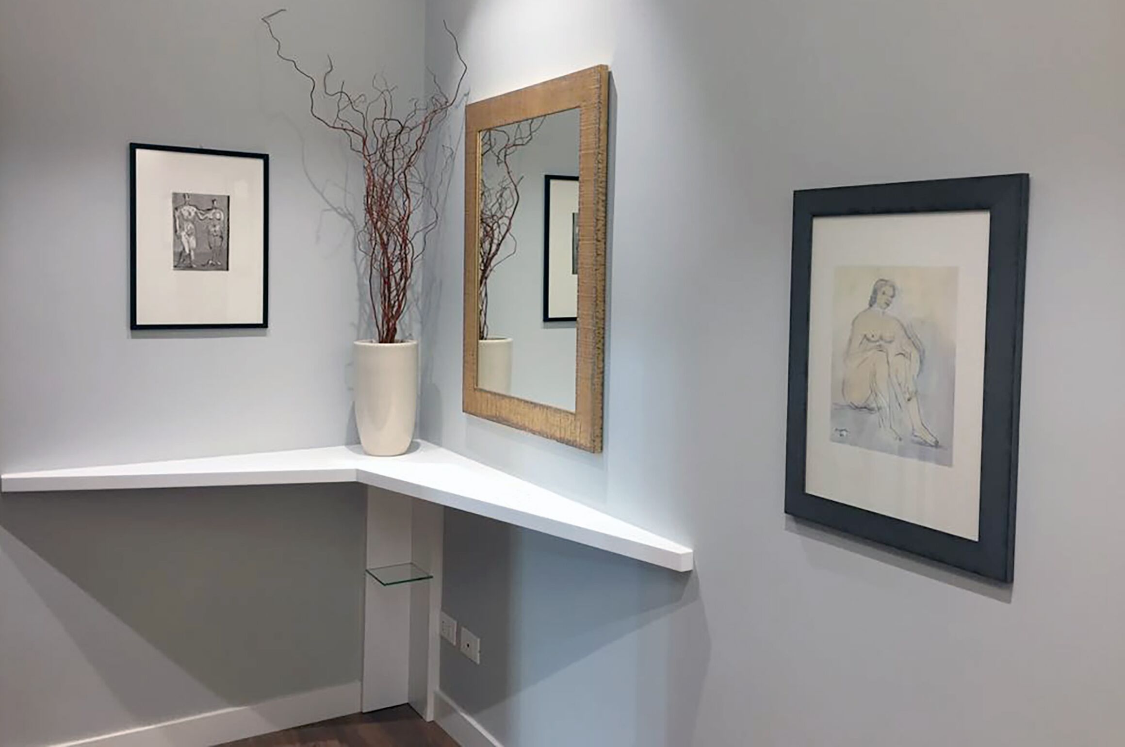 Un mur décoratif composé de tableaux encadrés et d’un miroir.