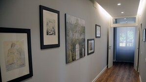 Un corridoio con opere d'arte incorniciate alle pareti e un pavimento in legno.