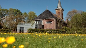 Una iglesia con un campanario alto y una extensión moderna con amplios ventanales.