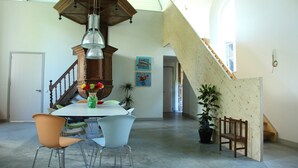Un comedor espacioso con techo alto, una escalera de madera y vistas a la habitación contigua.