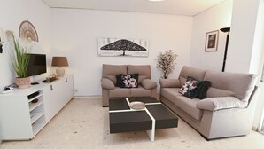 A living room with two sofas, a coffee table, a TV, a lamp, and decorative items. - A78 EDIFICIO PEÑASOL 1º 3 (Calpe)