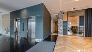 A modern lobby with a glass elevator, a staircase, and a wooden floor. - Wow-happy Hotel Taipei (Taipei)