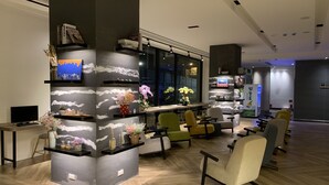 A modern interior with a central column, shelves with decorative items, and seating areas. - Wow-happy Hotel Taipei (Taipei)