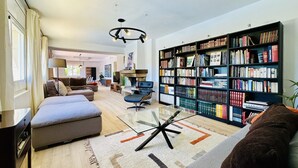 Un salon moderne avec un canapé, une table basse en verre, une bibliothèque et une cheminée.