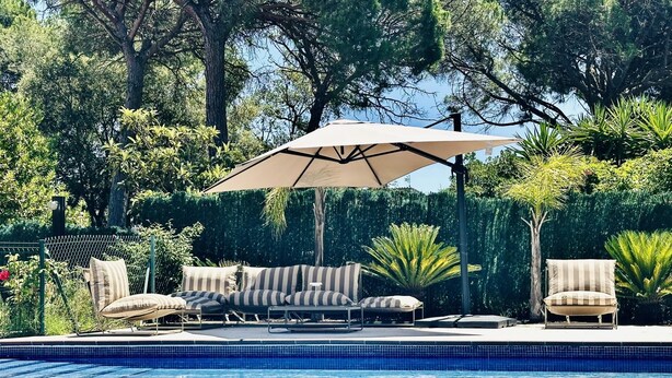 Une piscine avec des chaises longues et un parasol.