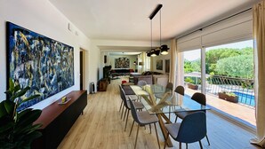 Un vaste espace de vie comprenant une table à manger, des chaises et une grande peinture abstraite accrochée au mur.