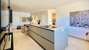 Une cuisine moderne dotée d’un îlot central, d’appareils électroménagers intégrés et d’un coin repas avec des chaises.