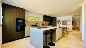 Une cuisine moderne dotée d’un îlot central, de tabourets de bar et d’un coin repas avec des chaises.