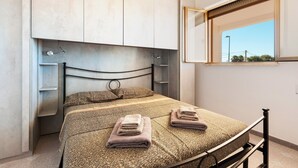 Een slaapkamer met een bed, een raam en een kledingkast.