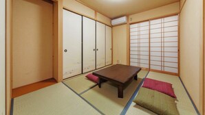 Una habitación japonesa tradicional con suelo de tatami, una mesa de madera baja, puertas correderas y un mampara shoji.