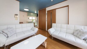 Una sala moderna con dos sofás blancos, una mesa de centro blanca y suelo de madera.