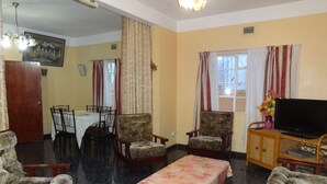 Un salon comprenant un coin repas, un téléviseur posé sur un meuble en bois et un tableau accroché au mur.