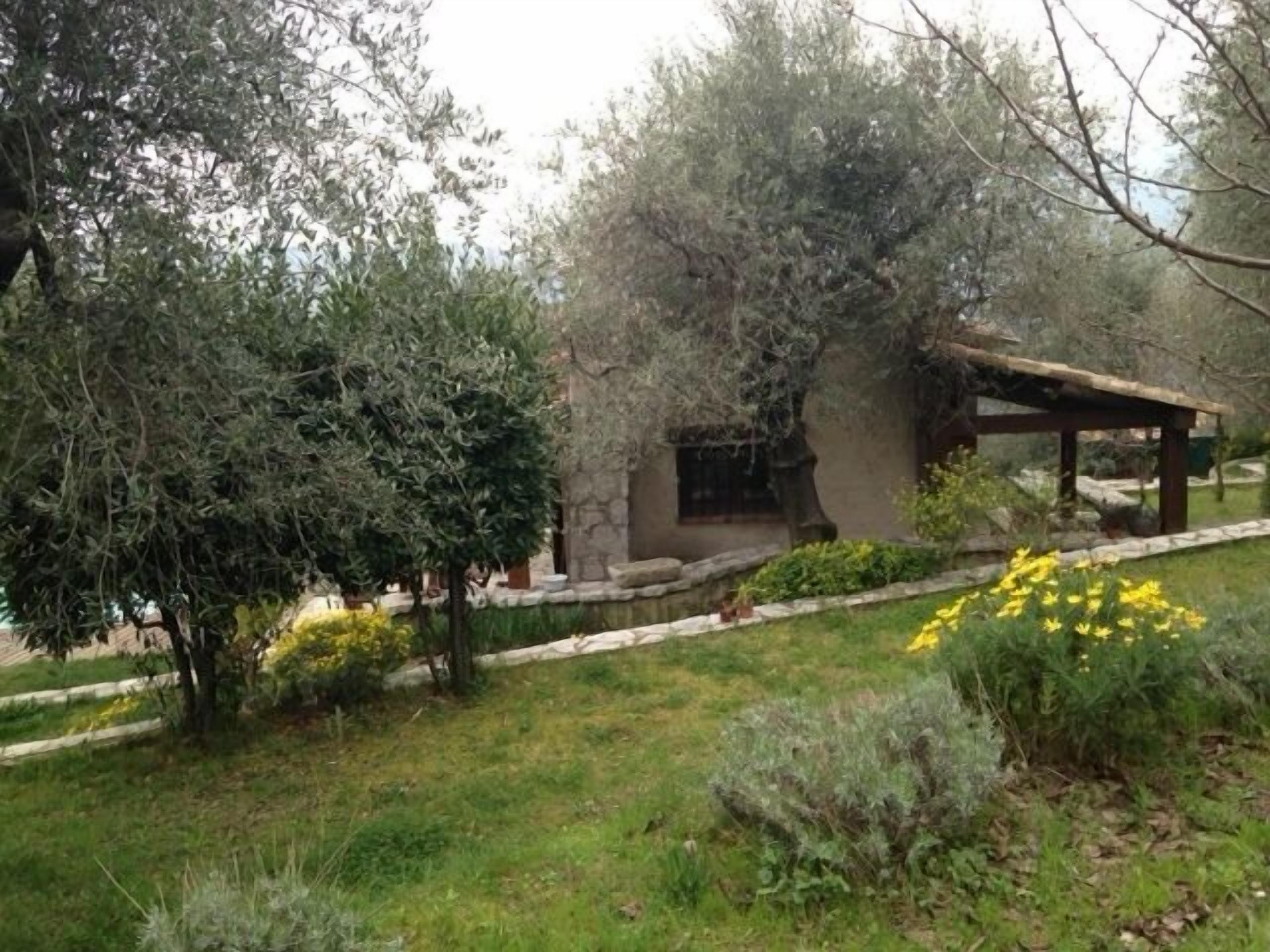 A rustic building with a stone exterior, surrounded by a well-maintained garden with various shrubs and yellow flowers.