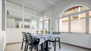 Ein Essbereich mit einem Tisch für vier Personen, umgeben von Stühlen, mit Blick auf ein Ziegelgebäude durch große Fenster.