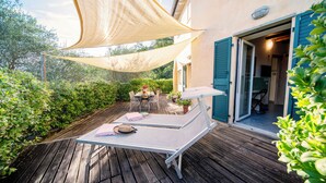 Une terrasse en bois avec une table et des chaises, un auvent et une porte donnant sur une pièce.