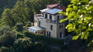 Une maison à plusieurs étages, dotée d’un panneau solaire sur le toit et entourée d’une végétation luxuriante.