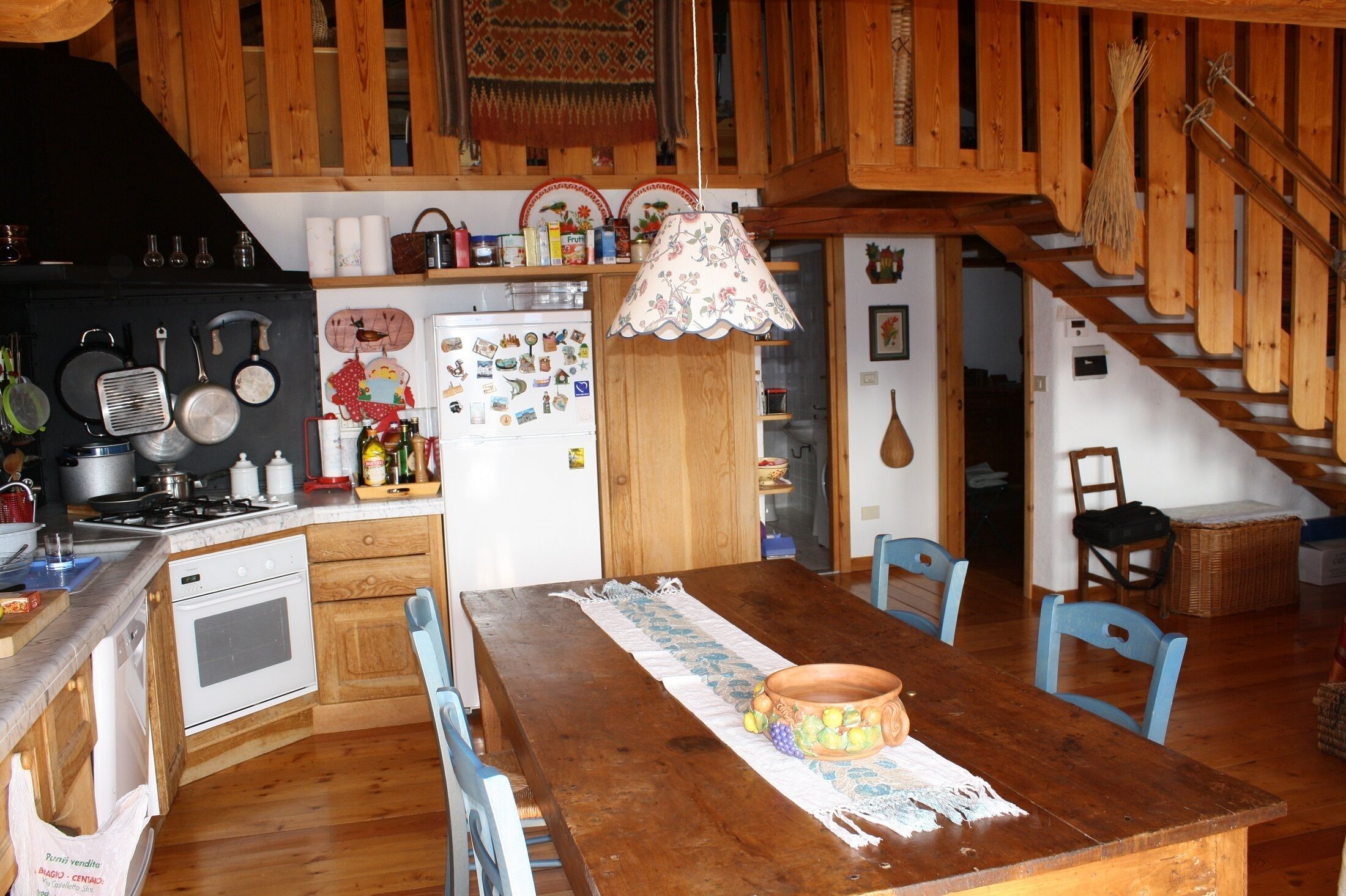 Een landelijke keuken met houten kastjes, een fornuis en een eettafel met stoelen.